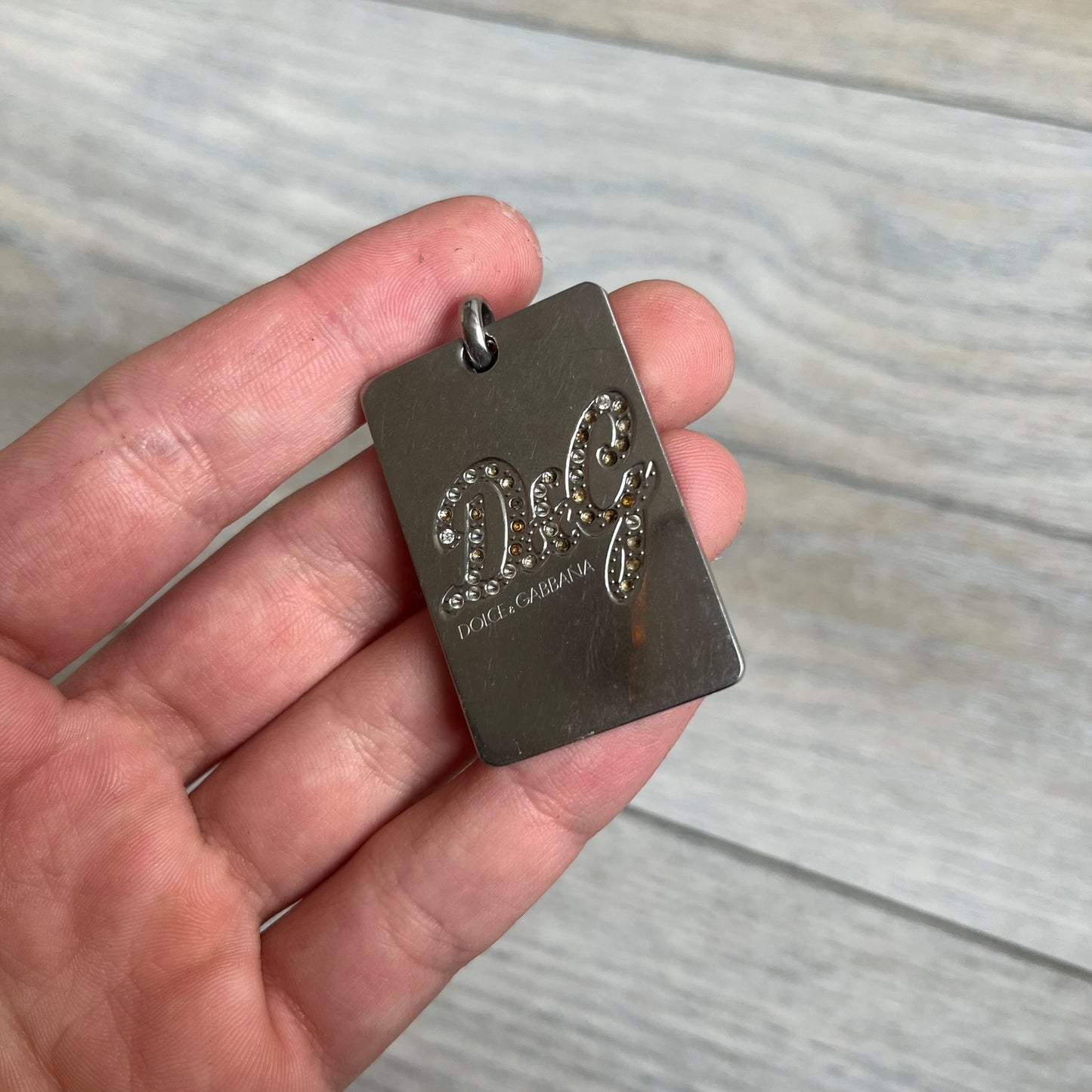 Dolce &amp; Gabbana Rhinestones Dog Tag Necklace DJ0704 crafted from polished stainless steel. Features a rectangular pendant with the iconic D&amp;G logo detailed in rhinestones, and “Dolce &amp; Gabbana” engraved subtly below. Comes with a basic non-D&amp;G steel ball chain.