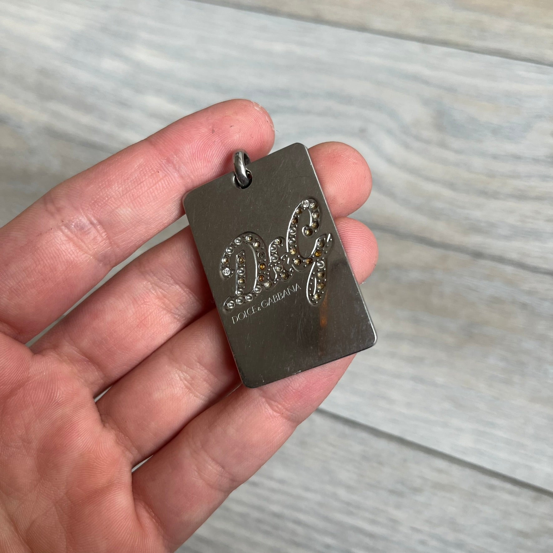 Dolce &amp; Gabbana Rhinestones Dog Tag Necklace DJ0704 crafted from polished stainless steel. Features a rectangular pendant with the iconic D&amp;G logo detailed in rhinestones, and “Dolce &amp; Gabbana” engraved subtly below. Comes with a basic non-D&amp;G steel ball chain.