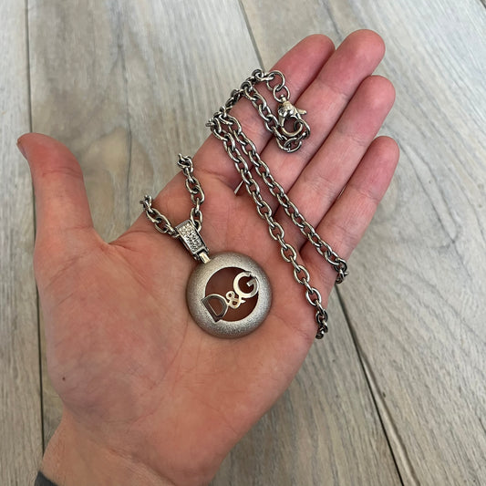 Dolce & Gabbana 2000s Round D&G Logo Necklace is a chain necklace featuring a lobster clasp closure and a thick 3D circular pendant with cut-out center and D&G logo in the middle. The pendant connector is embellished with crystal detailing. The necklace comes with a brown Dolce & Gabbana dust bag.