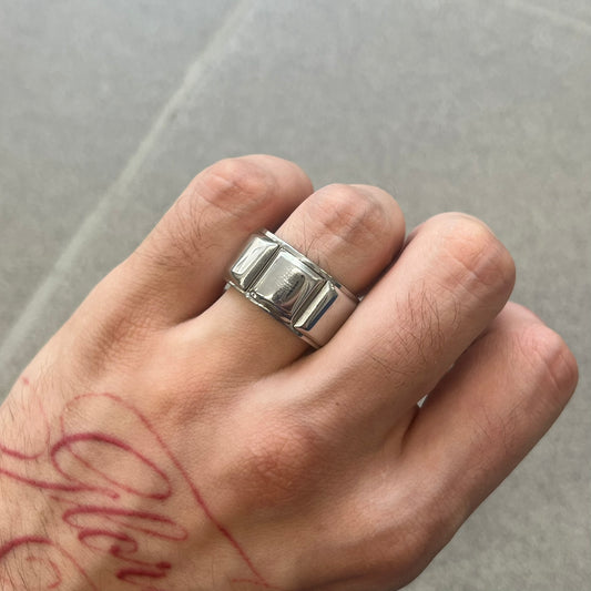 Dolce &amp; Gabbana DJ0836 Ring is made from silver-tone metal and features three raised square elements set across the top. Next to the squares, there is a small engraved D&amp;G logo. The ring has a clean, minimal design and is marked with model code DJ0836.