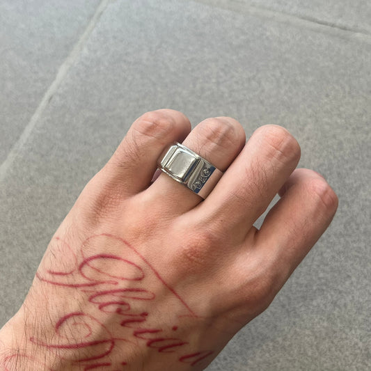 Dolce &amp; Gabbana DJ0836 Ring is made from silver-tone metal and features three raised square elements set across the top. Next to the squares, there is a small engraved D&amp;G logo. The ring has a clean, minimal design and is marked with model code DJ0836.