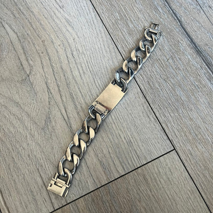 Dolce & Gabbana 2000’s Stainless Steel Bracelet DJ0552 is a thick bracelet made from stainless steel featuring large Cuban-style links. The center includes a plaque with a small engraved D&G logo, while the clasp is also marked with Dolce & Gabbana branding. The piece is referenced as DJ0552 and comes with the original box and dustbag.