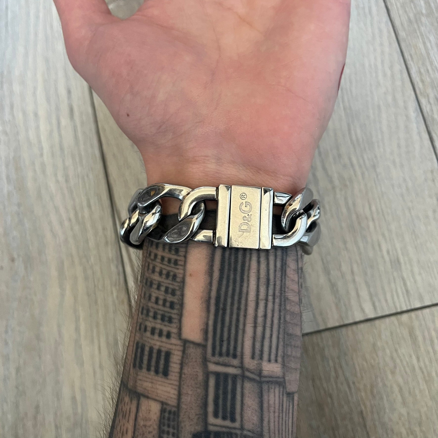 Dolce & Gabbana 2000’s Stainless Steel Bracelet DJ0552 is a thick bracelet made from stainless steel featuring large Cuban-style links. The center includes a plaque with a small engraved D&G logo, while the clasp is also marked with Dolce & Gabbana branding. The piece is referenced as DJ0552 and comes with the original box and dustbag.
