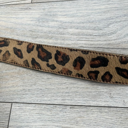 Dolce & Gabbana 2000s Studded Buckle Leopard Print Belt is a beige belt with an all-over leopard print and a short hair-textured exterior. The buckle features an italic-style D&G logo in a silver-tone finish with rhinestone detailing. The interior is finished in brown leather.