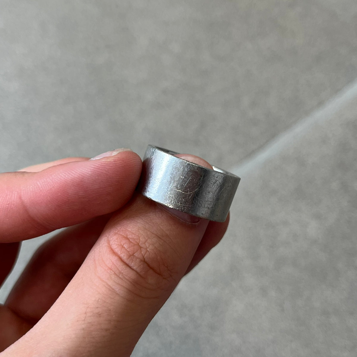Dolce & Gabbana 2000's Unclassifiable Ring features a minimal stainless steel design with an engraved D&G logo and tilted “Unclassifiable” text underneath on the front. The model number and D&G branding are engraved on the inside.
