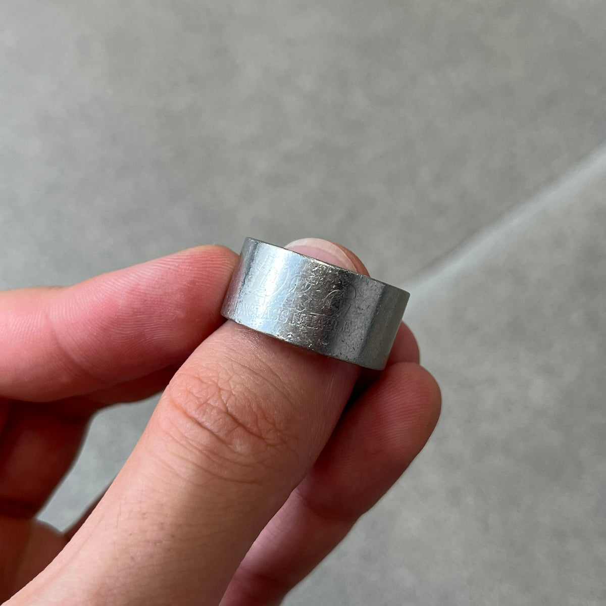 Dolce & Gabbana 2000's Unclassifiable Ring features a minimal stainless steel design with an engraved D&G logo and tilted “Unclassifiable” text underneath on the front. The model number and D&G branding are engraved on the inside.
