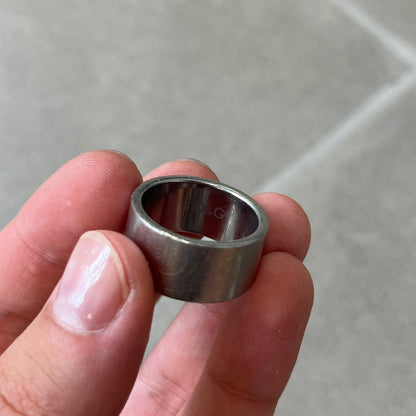 Dolce & Gabbana 2000's Unclassifiable Ring features a minimal stainless steel design with an engraved D&G logo and tilted “Unclassifiable” text underneath on the front. The model number and D&G branding are engraved on the inside.
