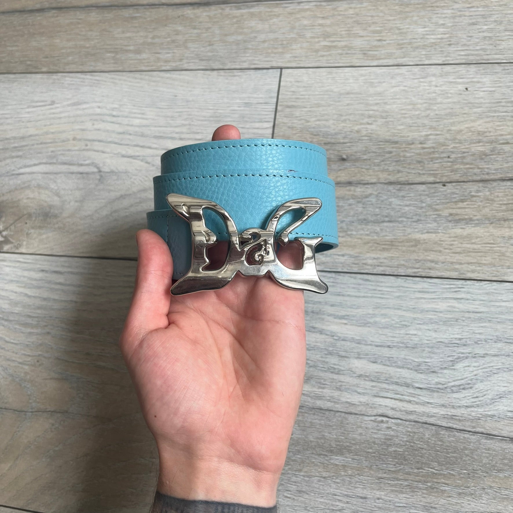 Dolce &amp; Gabbana 2008 Butterfly Buckle Baby Blue Leather Belt from the AW2008 collection. Crafted from smooth Baby Blue leather with visible edge stitching, this belt features a big silver-tone D&amp;G logo buckle shaped in a butterfly-style form. The buckle has a polished metal finish, while the belt itself is made from 100% leather and retains a clean, structured profile. An original seasonal accessory from Dolce &amp; Gabbana’s AW2008 season.