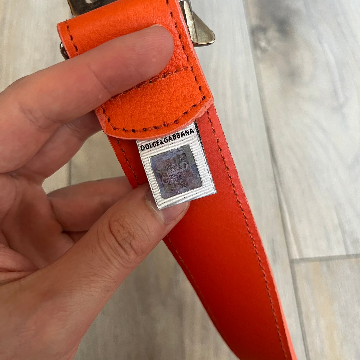 Dolce &amp; Gabbana 2008 Butterfly Buckle Orange Leather Belt from the AW2008 collection. Crafted from smooth orange leather with visible edge stitching, this belt features a big silver-tone D&amp;G logo buckle shaped in a butterfly-style form. The buckle has a polished metal finish, while the belt itself is made from 100% leather and retains a clean, structured profile. An original seasonal accessory from Dolce &amp; Gabbana’s AW2008 season.