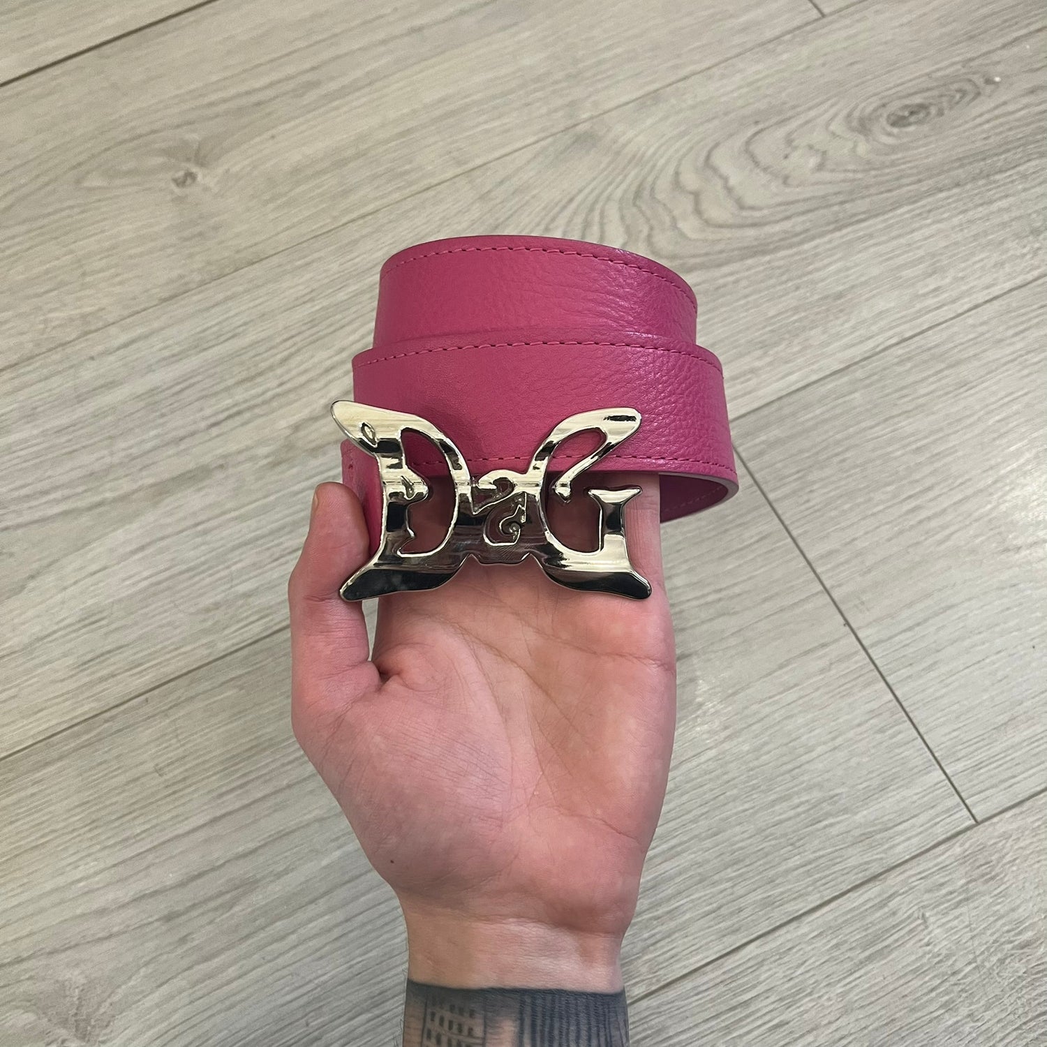 Dolce &amp; Gabbana 2008 Butterfly Buckle Pink Leather Belt from the AW2008 collection. Crafted from smooth pink leather with visible edge stitching, this belt features a big silver-tone D&amp;G logo buckle shaped in a butterfly-style form. The buckle has a polished metal finish, while the belt itself is made from 100% leather and retains a clean, structured profile. An original seasonal accessory from Dolce &amp; Gabbana’s AW2008 season.