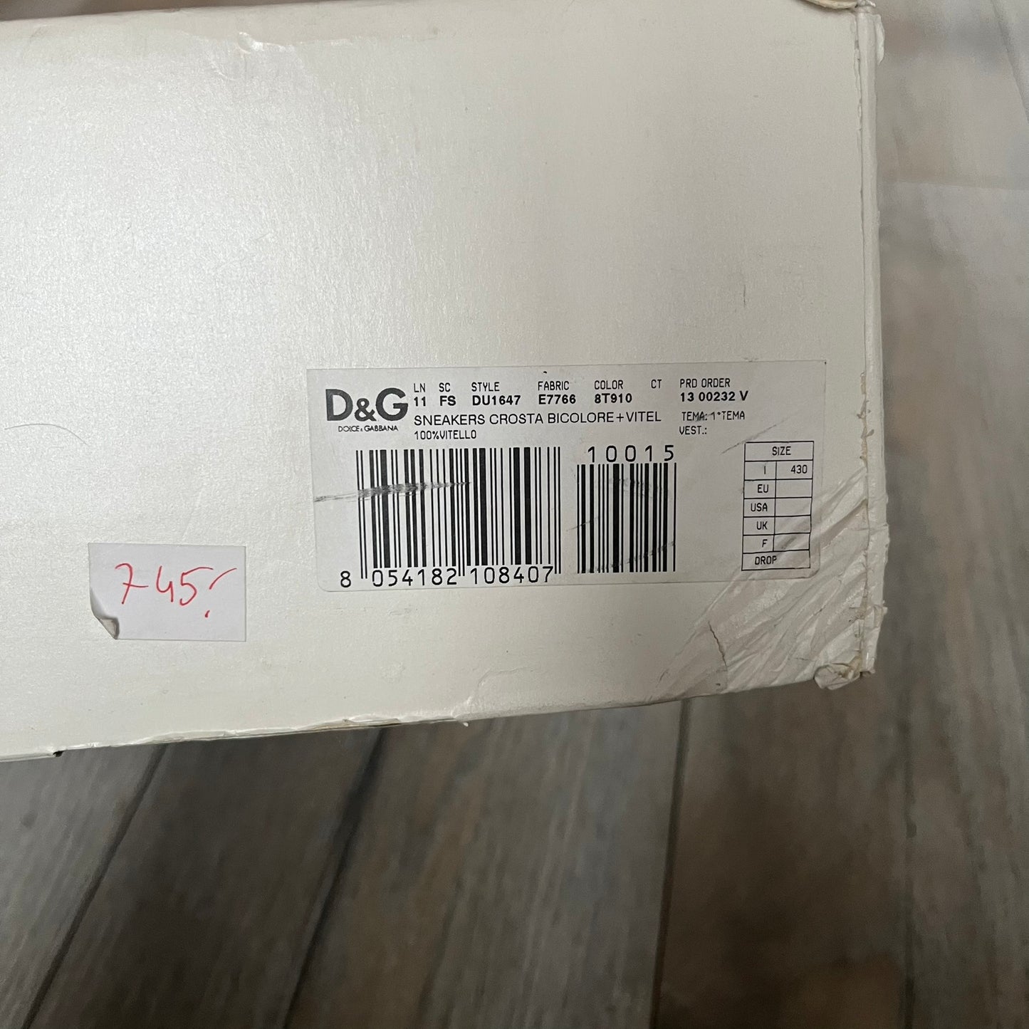 Dolce & Gabbana 2013 Bicolor Sneakers are black leather sneakers with a brown rubber sole. They feature red leather stripes on the sides, tongue details, and a back stripe, with black D&G logos on the sides and tongue. The sneakers come with the original box and tags.