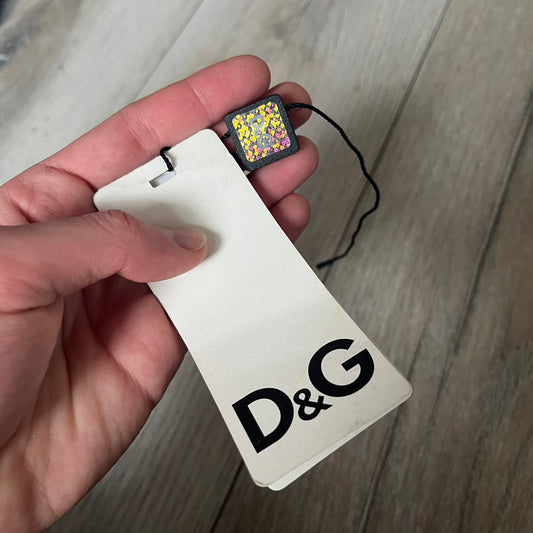 Dolce & Gabbana 2013 Bicolor Sneakers are black leather sneakers with a brown rubber sole. They feature red leather stripes on the sides, tongue details, and a back stripe, with black D&G logos on the sides and tongue. The sneakers come with the original box and tags.