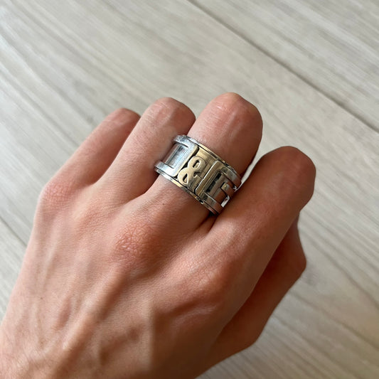 Dolce &amp; Gabbana 3D logo ring crafted in silver-tone metal with a unique two-part construction. The base is a classic band, topped with a raised layer that wraps the D&amp;G logo around the ring. Designed with a movable top section that spins, it’s a dynamic accessory merging playful function with signature branding.