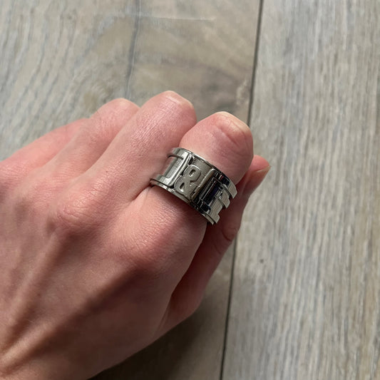 Dolce &amp; Gabbana 3D logo ring crafted in silver-tone metal with a unique two-part construction. The base is a classic band, topped with a raised layer that wraps the D&amp;G logo around the ring. Designed with a movable top section that spins, it’s a dynamic accessory merging playful function with signature branding.