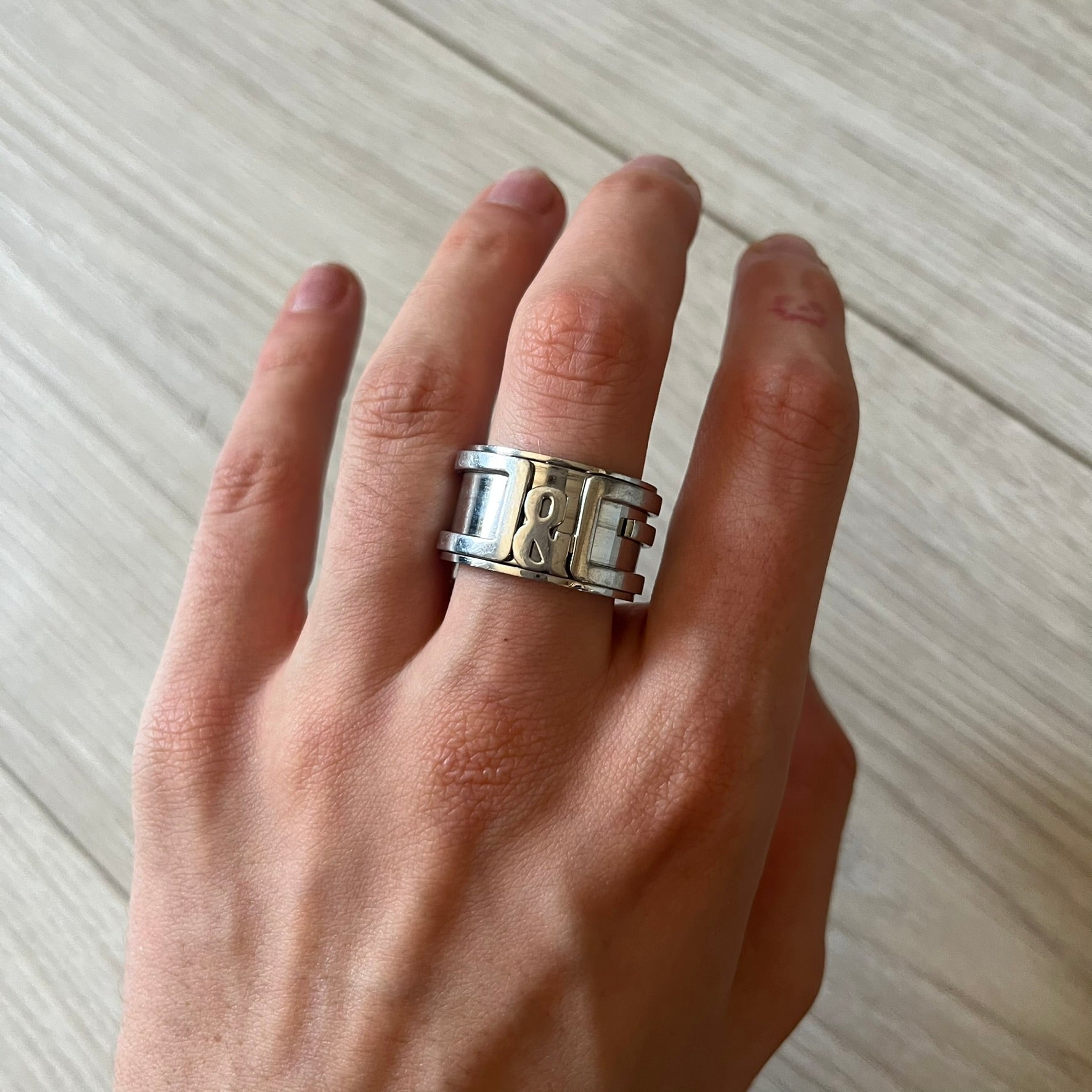 Dolce &amp; Gabbana 3D logo ring crafted in silver-tone metal with a unique two-part construction. The base is a classic band, topped with a raised layer that wraps the D&amp;G logo around the ring. Designed with a movable top section that spins, it’s a dynamic accessory merging playful function with signature branding.