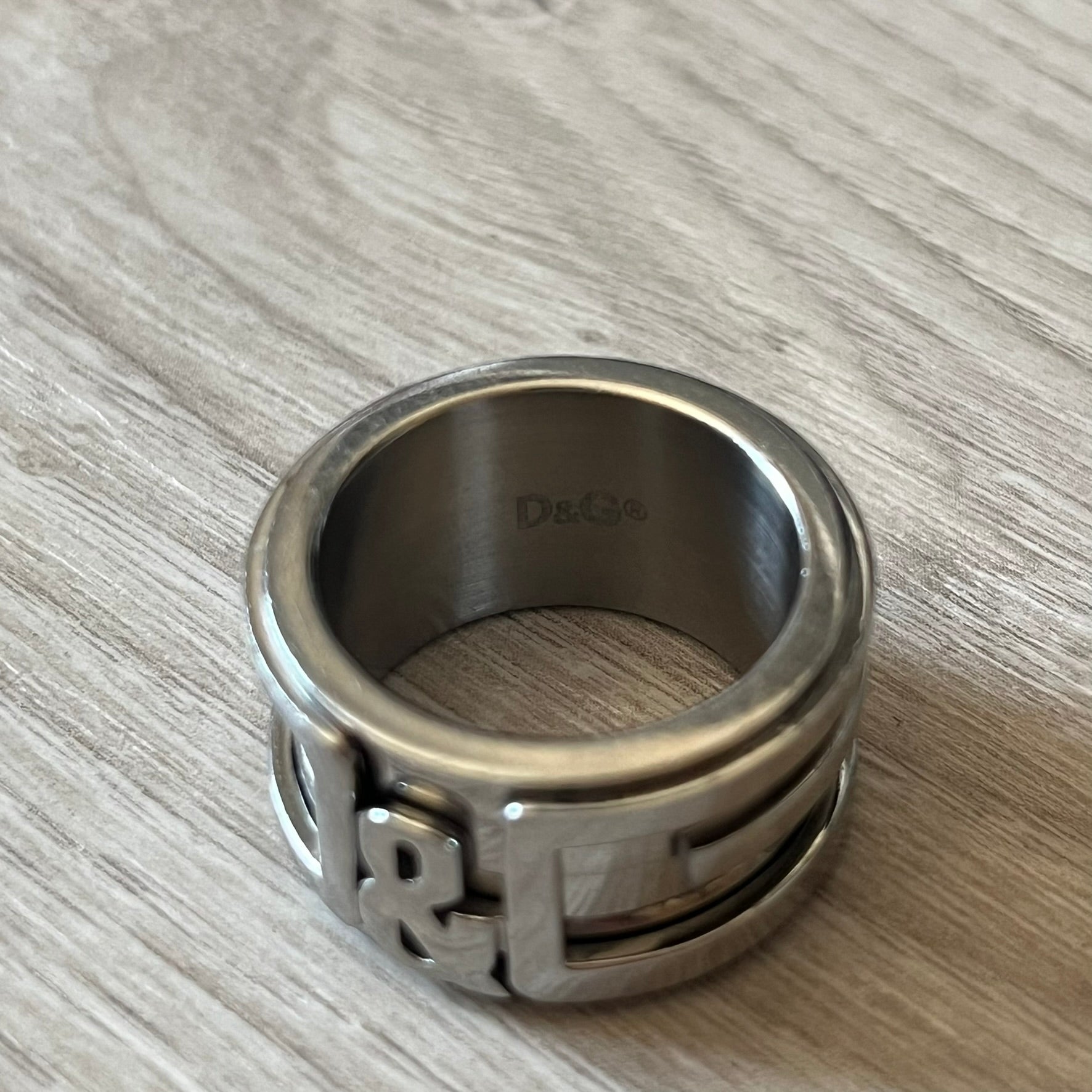 Dolce &amp; Gabbana 3D logo ring crafted in silver-tone metal with a unique two-part construction. The base is a classic band, topped with a raised layer that wraps the D&amp;G logo around the ring. Designed with a movable top section that spins, it’s a dynamic accessory merging playful function with signature branding.