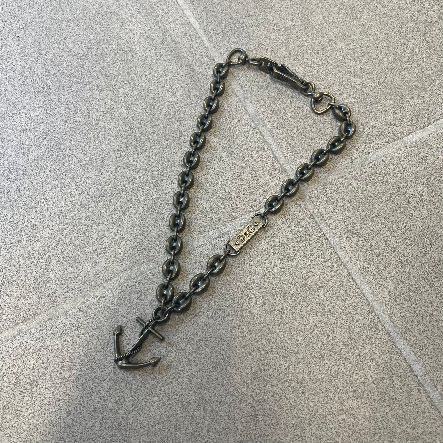 Dolce &amp; Gabbana AW2006 Anchor Necklace features a thick, heavy necklace with a dirty gold-tone finish and oversized mariner links. One of the links is detailed with an engraved D&amp;G logo plaque. The main pendant is a large anchor wrapped with a rope motif, matching the rugged nautical-inspired design of the necklace.