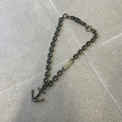 Dolce &amp; Gabbana AW2006 Anchor Necklace features a thick, heavy necklace with a dirty gold-tone finish and oversized mariner links. One of the links is detailed with an engraved D&amp;G logo plaque. The main pendant is a large anchor wrapped with a rope motif, matching the rugged nautical-inspired design of the necklace.