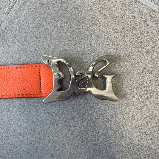 Dolce &amp; Gabbana 2008 Butterfly Buckle Orange Leather Belt from the AW2008 collection. Crafted from smooth orange leather with visible edge stitching, this belt features a big silver-tone D&amp;G logo buckle shaped in a butterfly-style form. The buckle has a polished metal finish, while the belt itself is made from 100% leather and retains a clean, structured profile. An original seasonal accessory from Dolce &amp; Gabbana’s AW2008 season.