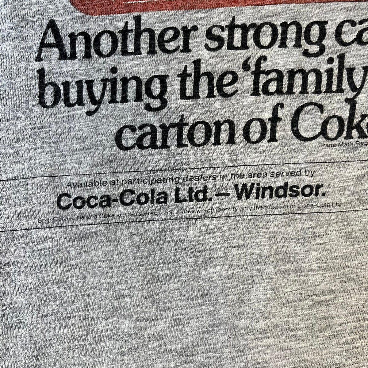 Dolce & Gabbana AW2011 Coca Cola Tee is a gray T-shirt made in collaboration with Coca-Cola, featuring a vintage promo-style graphic on the front of a six-pack of Coca-Cola bottles with “Introducing our new plastic carrier” text. It has licensed tags and a small black D&G logo on the upper back.