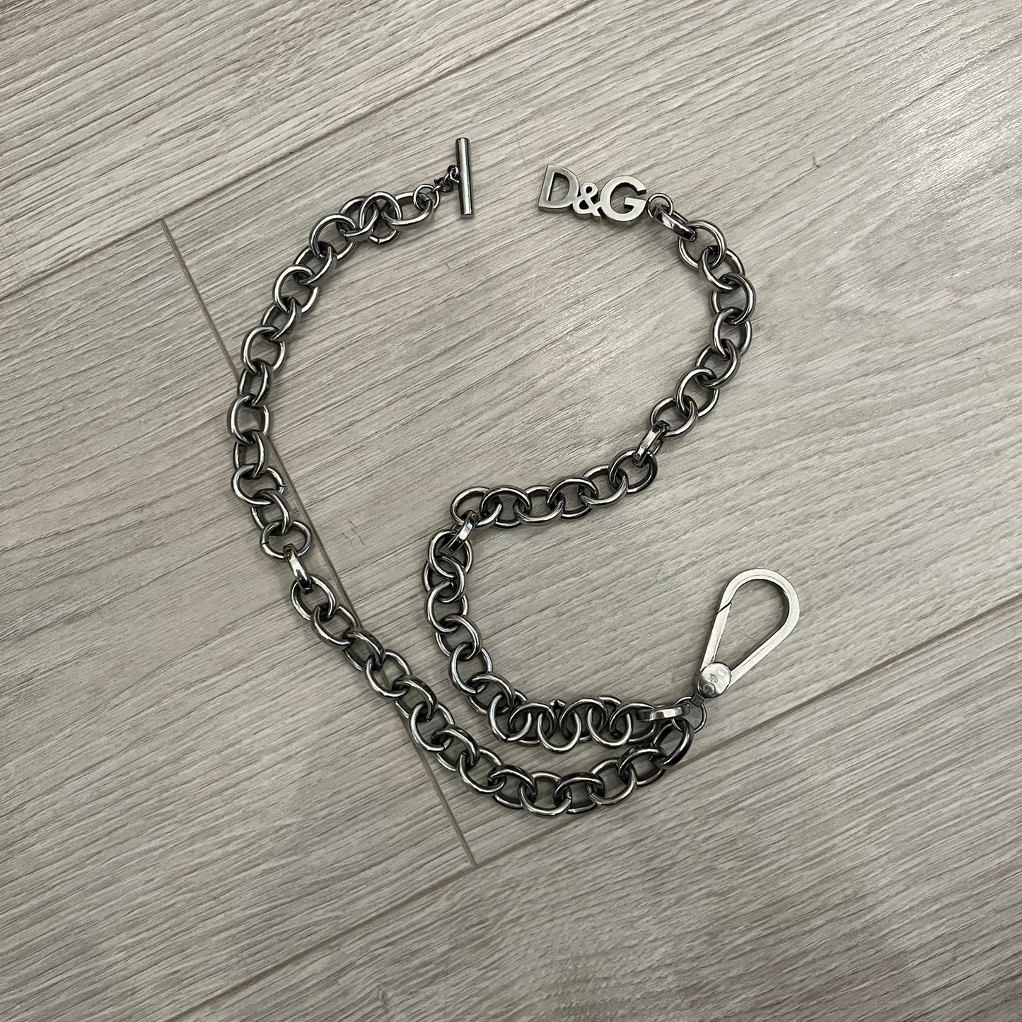 Dolce &amp; Gabbana Carabiner Chain Necklace features a robust stainless steel chain with a central carabiner engraved with the D&amp;G logo. The adjustable design includes a bolt-style clasp to modify the length, and the opposite end showcases a three-dimensional D&amp;G logo, blending industrial detailing with high-fashion appeal.