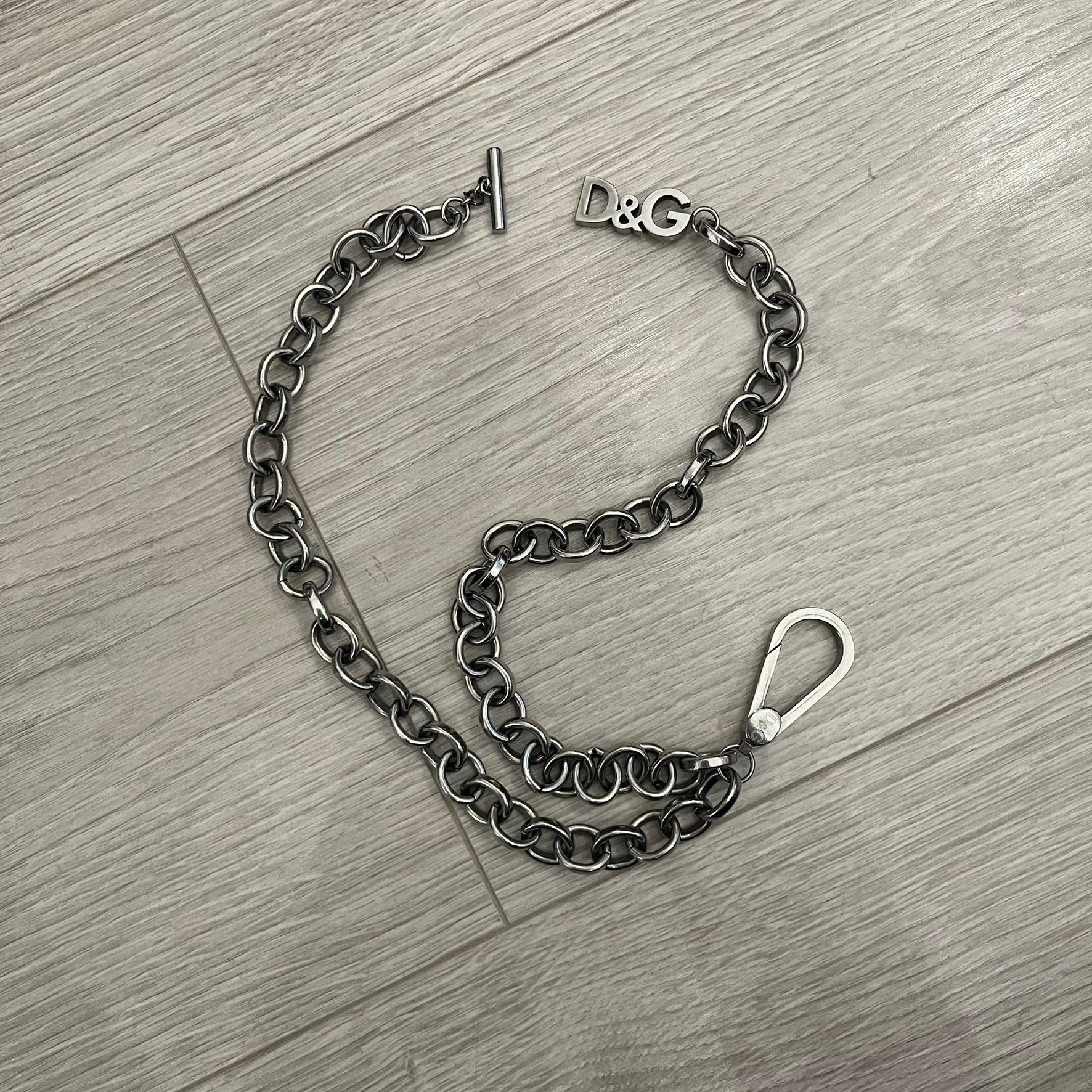 Dolce &amp; Gabbana Carabiner Chain Necklace features a robust stainless steel chain with a central carabiner engraved with the D&amp;G logo. The adjustable design includes a bolt-style clasp to modify the length, and the opposite end showcases a three-dimensional D&amp;G logo, blending industrial detailing with high-fashion appeal.