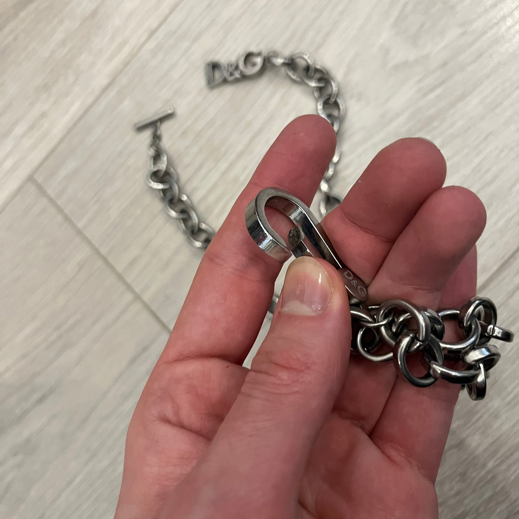 Dolce &amp; Gabbana Carabiner Chain Necklace features a robust stainless steel chain with a central carabiner engraved with the D&amp;G logo. The adjustable design includes a bolt-style clasp to modify the length, and the opposite end showcases a three-dimensional D&amp;G logo, blending industrial detailing with high-fashion appeal.