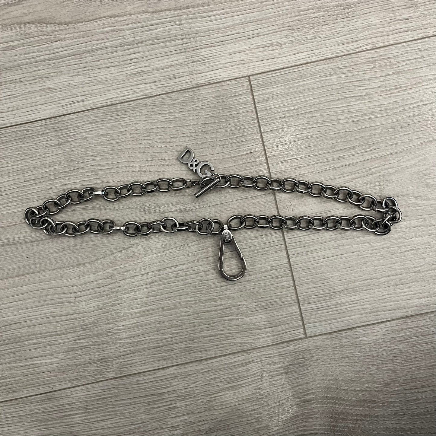 Dolce &amp; Gabbana Carabiner Chain Necklace features a robust stainless steel chain with a central carabiner engraved with the D&amp;G logo. The adjustable design includes a bolt-style clasp to modify the length, and the opposite end showcases a three-dimensional D&amp;G logo, blending industrial detailing with high-fashion appeal.