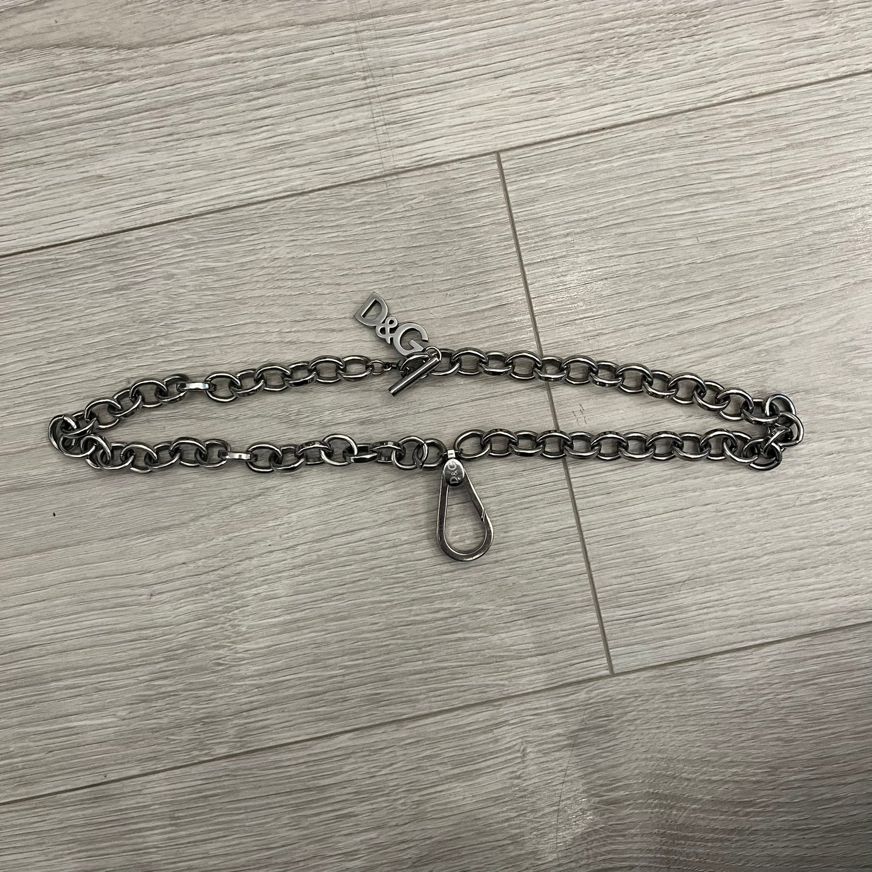 Dolce &amp; Gabbana Carabiner Chain Necklace features a robust stainless steel chain with a central carabiner engraved with the D&amp;G logo. The adjustable design includes a bolt-style clasp to modify the length, and the opposite end showcases a three-dimensional D&amp;G logo, blending industrial detailing with high-fashion appeal.