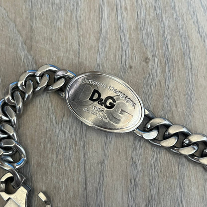 Dolce &amp; Gabbana Champagne Bracelet DJ1092 is a stainless steel bracelet. The silver-tone metal plate is shaped like a D&amp;G champagne label and displays a black D&amp;G logo, along with engraved “Glamorous Champagne 1994 Alc. 12% by Vol.” text. The back of the plate features a large, shallow engraved D&amp;G logo. Retailed at 125 usd in 2000's.