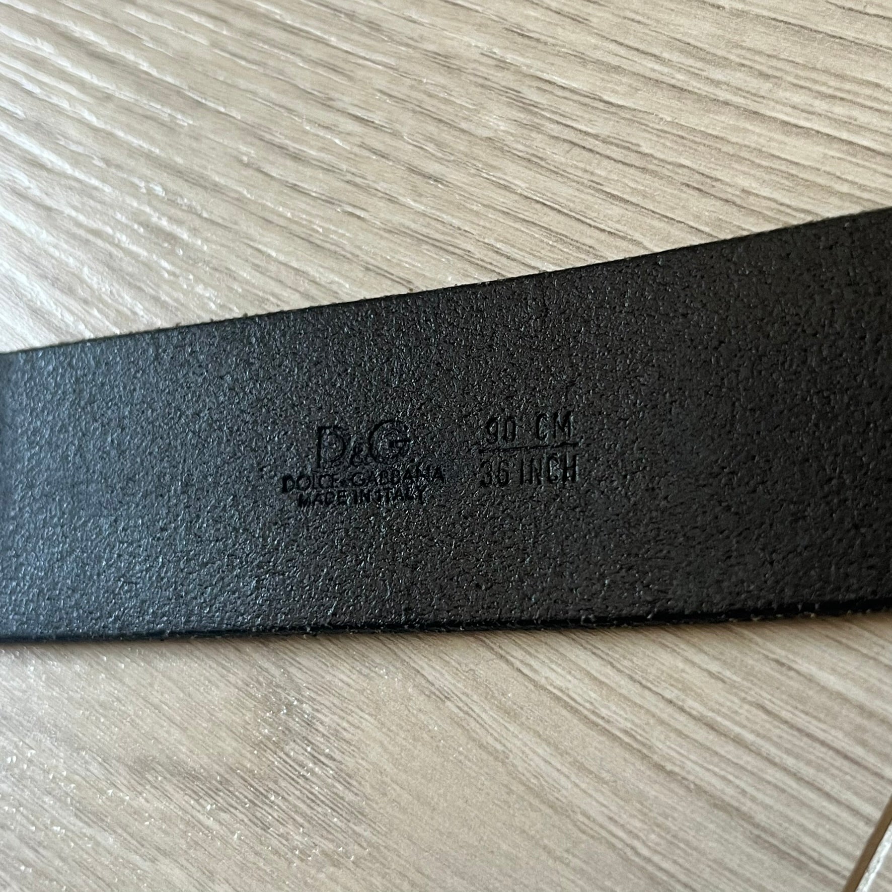  Dolce &amp; Gabbana “College Since 1994” belt featuring a pretty big crest-shaped buckle. The silver text overlays a white-and-black split crest, paired with a soft black leather strap for a refined yet edgy finish.