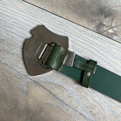 Dolce &amp; Gabbana “College Since 1994” belt featuring a big crest-shaped buckle. The silver text overlays a beige-and-black diagonally split crest, paired with a soft green leather strap in a washed style.