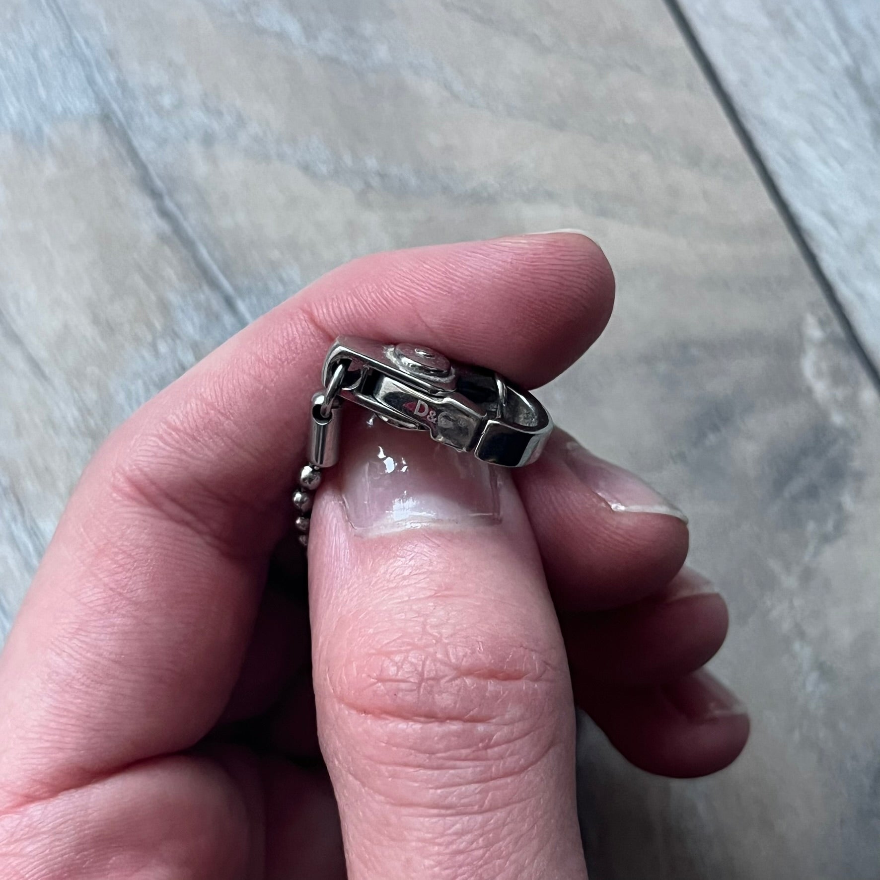 The Dolce & Gabbana Crystal Logo Dog Tag Necklace features a silver-tone ball chain with two pendants: a plain dog tag and a cutout D&G logo adorned with crystals. It has a large clasp engraved with D&G and model markings, from the 2000s.