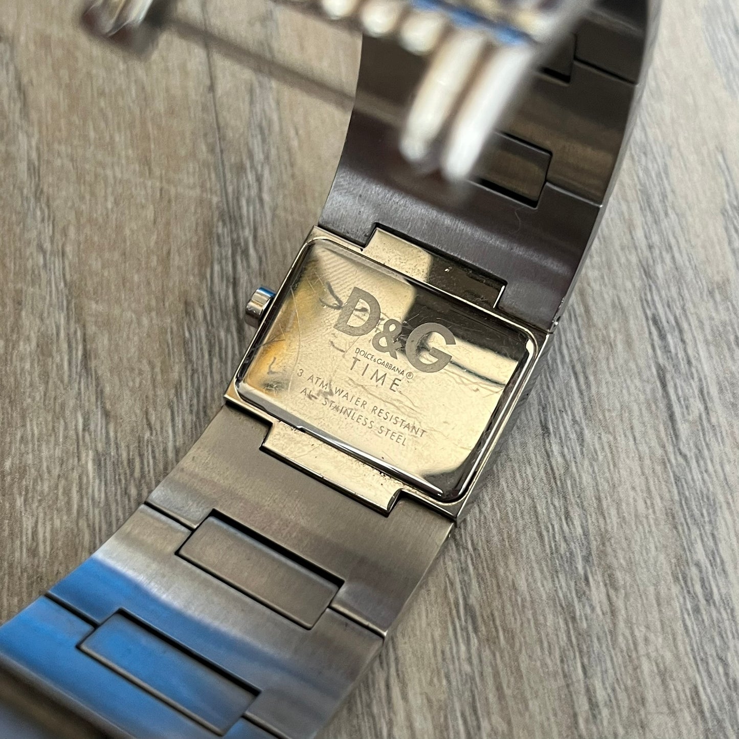 Dolce &amp; Gabbana Crystals Analog Watch is a stainless steel quartz watch featuring a square dial with fully crystal face, silver hands and small D&amp;G logo. The case and bracelet form a continuous design with the face matching the width of the bracelet. The bracelet is made from small silver rectangles. It includes a dual side-clasp closure, is water resistant to 3 ATM, with removable links. Comes with an extra link.