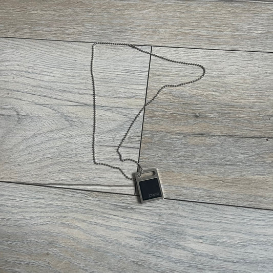 Dolce & Gabbana DJ0430 Black Stone Necklace is a 2000s necklace featuring a stainless steel pendant with a square black stone insert on the front. The lower right corner of the stone is engraved with a D&G logo. It comes with a steel ball chain.