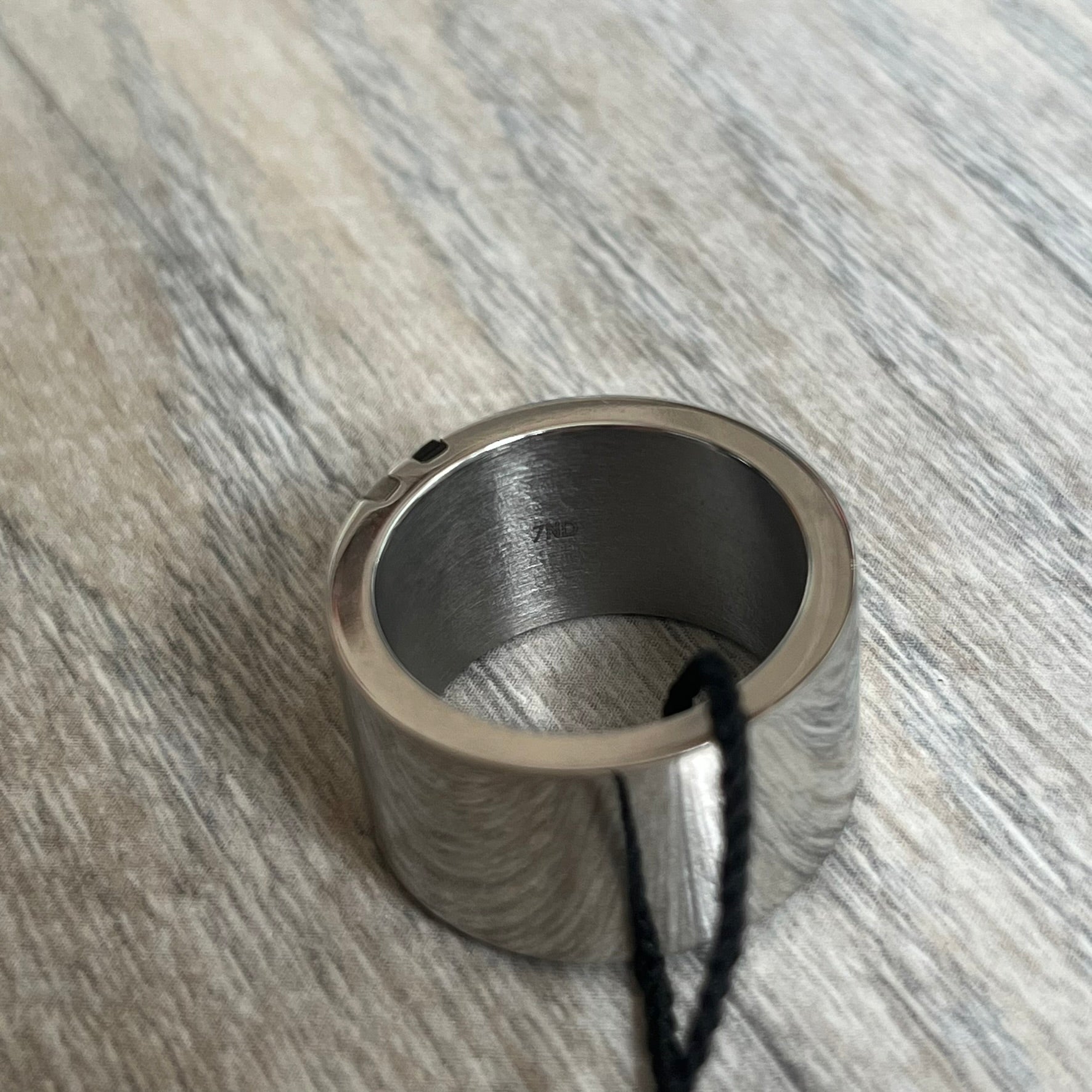 Dolce & Gabbana DJ0551 3 Lines Ring is a stainless steel ring featuring an engraved D&G logo placed vertically along the band. Next to the logo are three parallel lines in black, grey, and white. The design is minimal with a smooth metal finish.