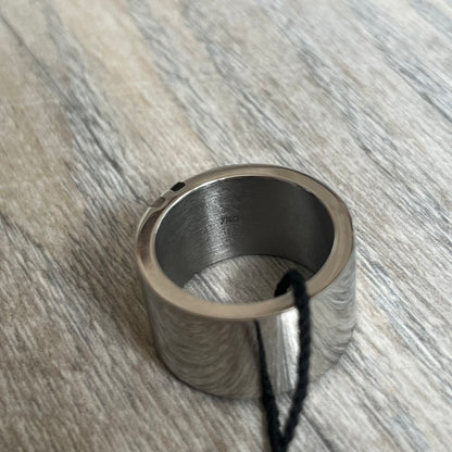 Dolce & Gabbana DJ0551 3 Lines Ring is a stainless steel ring featuring an engraved D&G logo placed vertically along the band. Next to the logo are three parallel lines in black, grey, and white. The design is minimal with a smooth metal finish.