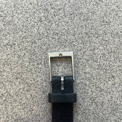 Dolce & Gabbana DJ0574 Black Stone Bracelet is a black leather bracelet featuring a stainless steel central plaque. The plaque includes a rectangular black stone detail with an engraved D&G logo on the right side. The clasp is also engraved with the D&G logo, completing the minimal design.
