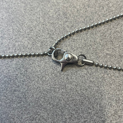 Dolce & Gabbana DJ0637 Gold Heart Necklace features a silver-tone stainless steel ball chain with a dog tag-style pendant. The pendant is engraved with a subtle "I" above a gold-tone heart secured by three visible screws, with "D&G" engraved below to form the "I ❤️ D&G" design. The back of the pendant has a "K.O" engraving from a previous owner. Comes with the original dust bag.
