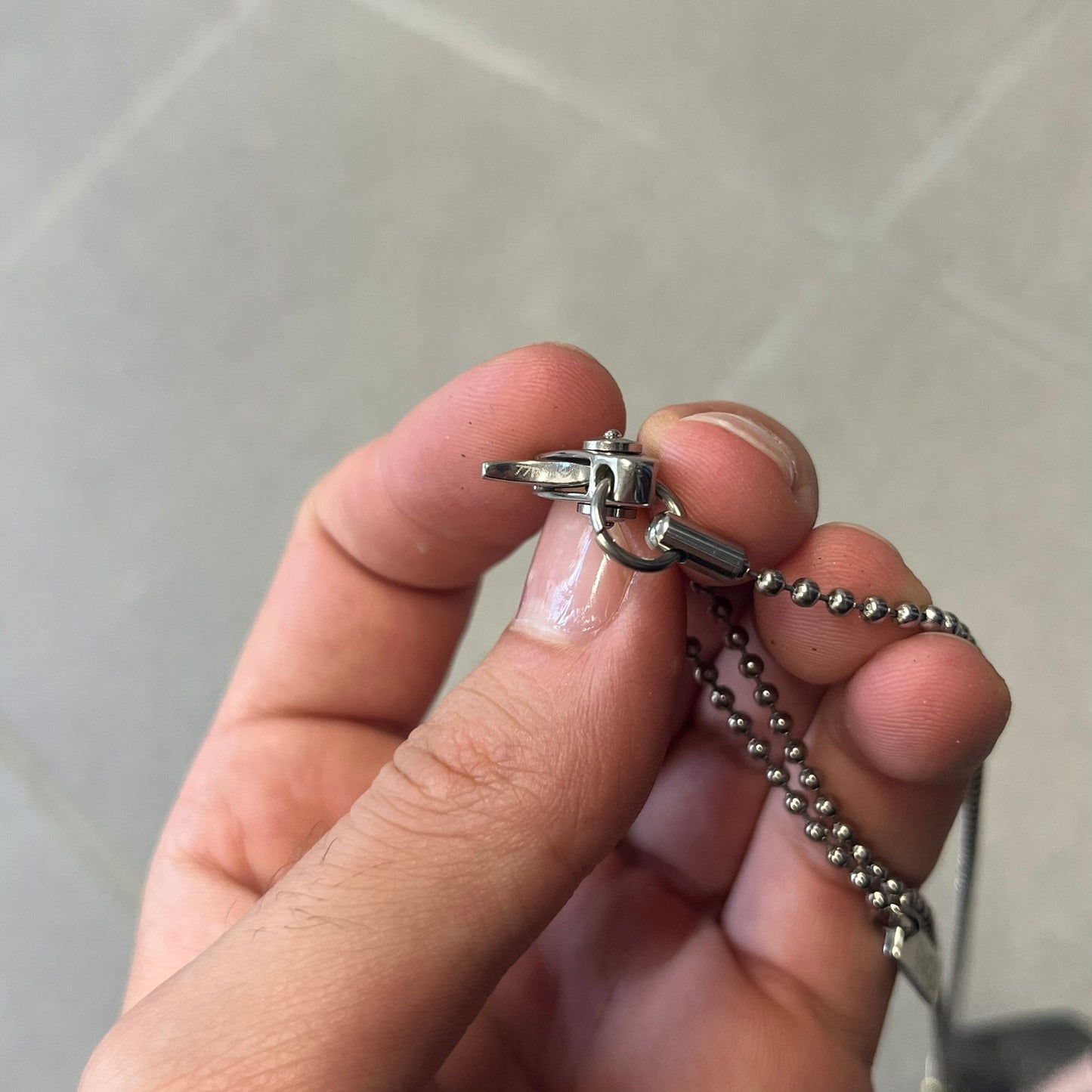 Dolce & Gabbana DJ0637 Gold Heart Necklace features a silver-tone stainless steel ball chain with a dog tag-style pendant. The pendant is engraved with a subtle "I" above a gold-tone heart secured by three visible screws, with "D&G" engraved below to form the "I ❤️ D&G" design. The back of the pendant has a "K.O" engraving from a previous owner. Comes with the original dust bag.
