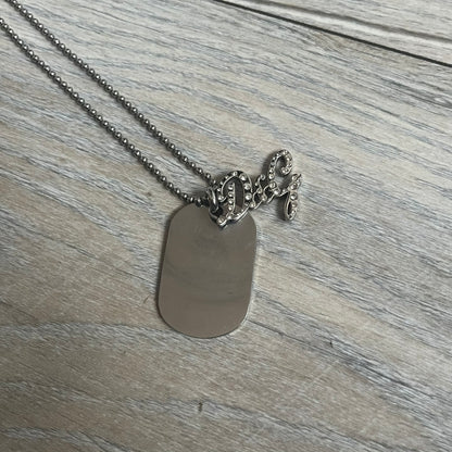 The Dolce &amp; Gabbana Crystal Logo Dog Tag Necklace features a silver-tone ball chain with two pendants: a plain dog tag and a cutout D&amp;G logo adorned with crystals. It has a large clasp engraved with D&amp;G and model markings, from the 2000s.