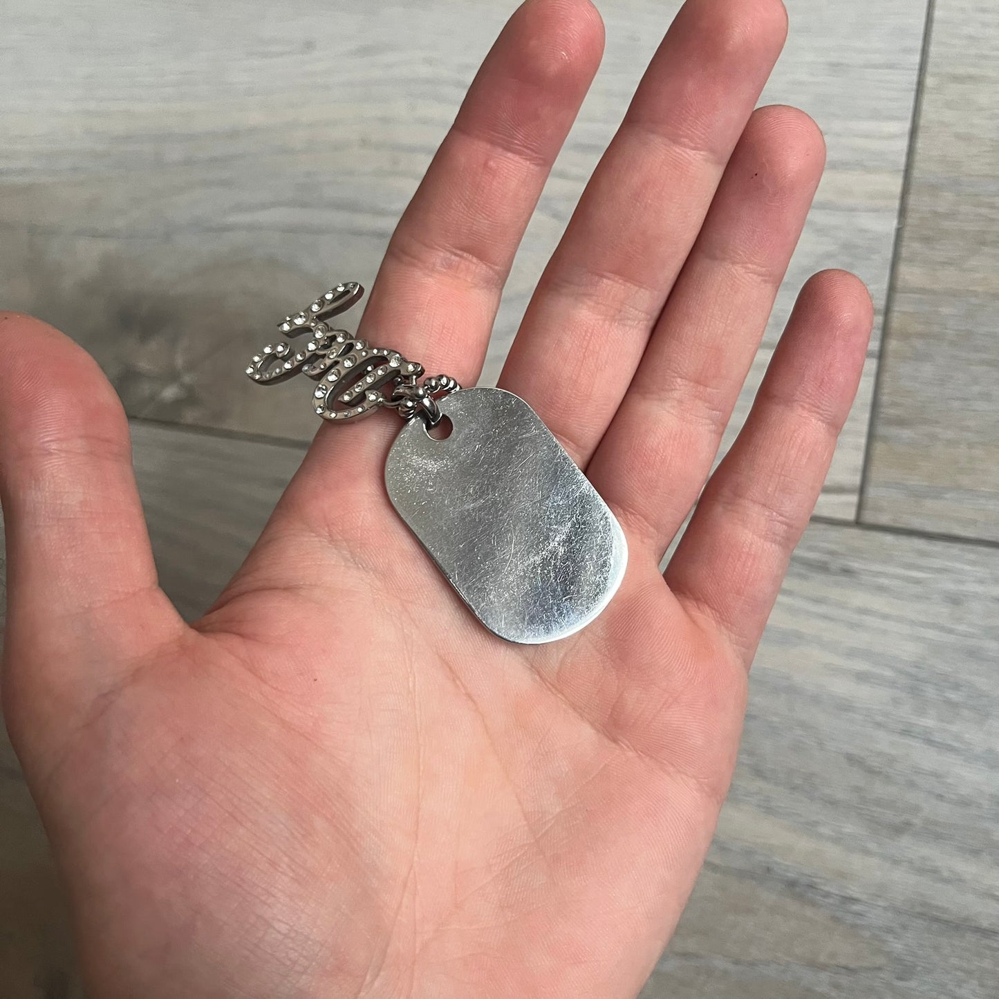 The Dolce &amp; Gabbana Crystal Logo Dog Tag Necklace features a silver-tone ball chain with two pendants: a plain dog tag and a cutout D&amp;G logo adorned with crystals. It has a large clasp engraved with D&amp;G and model markings, from the 2000s.