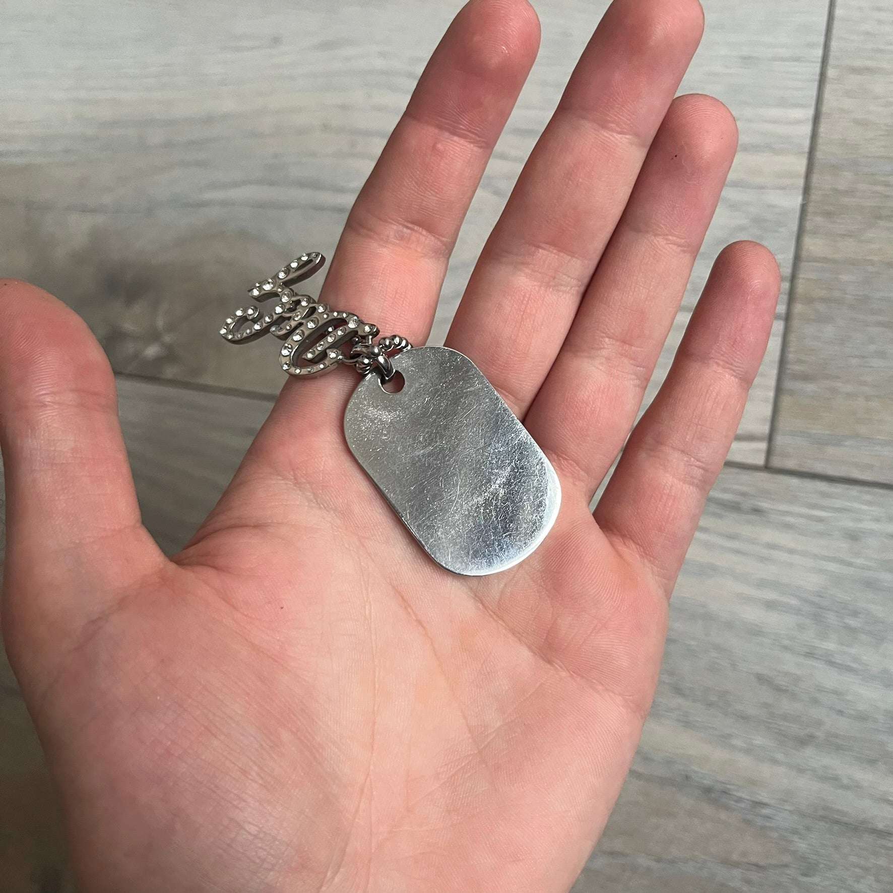 The Dolce &amp; Gabbana Crystal Logo Dog Tag Necklace features a silver-tone ball chain with two pendants: a plain dog tag and a cutout D&amp;G logo adorned with crystals. It has a large clasp engraved with D&amp;G and model markings, from the 2000s.