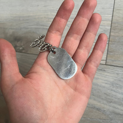 The Dolce &amp; Gabbana Crystal Logo Dog Tag Necklace features a silver-tone ball chain with two pendants: a plain dog tag and a cutout D&amp;G logo adorned with crystals. It has a large clasp engraved with D&amp;G and model markings, from the 2000s.