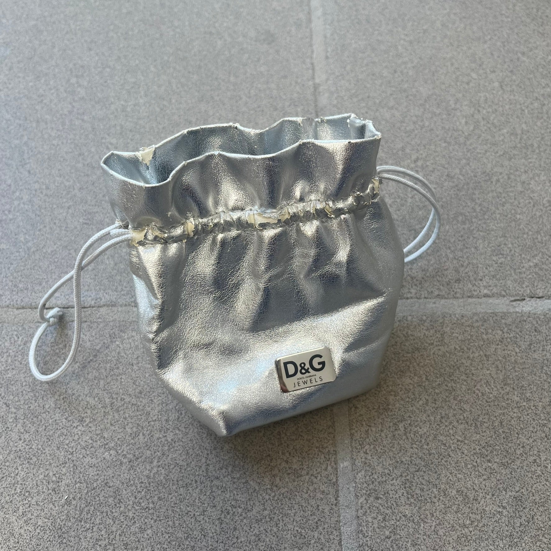 The Dolce &amp; Gabbana Crystal Logo Dog Tag Necklace features a silver-tone ball chain with two pendants: a plain dog tag and a cutout D&amp;G logo adorned with crystals. It has a large clasp engraved with D&amp;G and model markings, from the 2000s.
