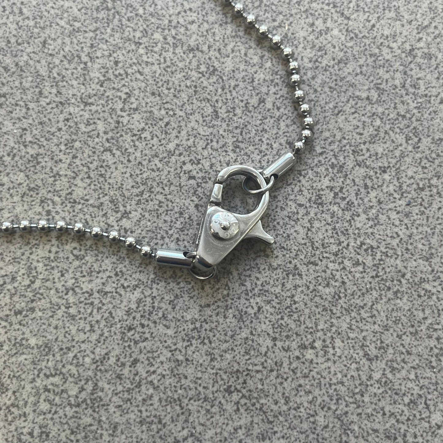 The Dolce &amp; Gabbana Crystal Logo Dog Tag Necklace features a silver-tone ball chain with two pendants: a plain dog tag and a cutout D&amp;G logo adorned with crystals. It has a large clasp engraved with D&amp;G and model markings, from the 2000s.