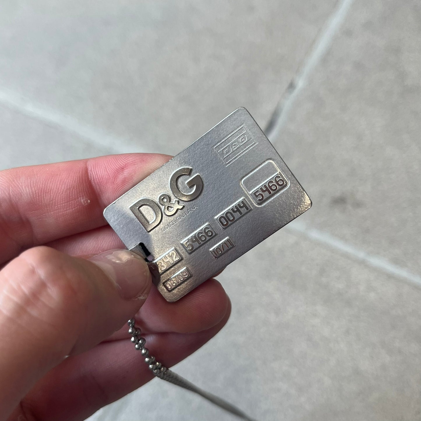 Dolce &amp; Gabbana 2000s Credit Card Necklace (DJ0772) is a rare stainless steel necklace featuring a credit card-shaped pendant. The pendant includes a large raised D&amp;G logo, an engraved D&amp;G logo, and embossed numbers inspired by a real credit card. The chain is not D&amp;G - it's a basic steel ball chain, only the pendant is from Dolce.