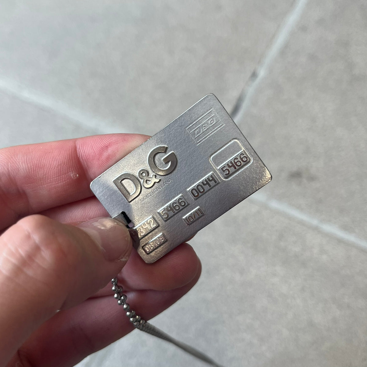 Dolce &amp; Gabbana 2000s Credit Card Necklace (DJ0772) is a rare stainless steel necklace featuring a credit card-shaped pendant. The pendant includes a large raised D&amp;G logo, an engraved D&amp;G logo, and embossed numbers inspired by a real credit card. The chain is not D&amp;G - it's a basic steel ball chain, only the pendant is from Dolce.