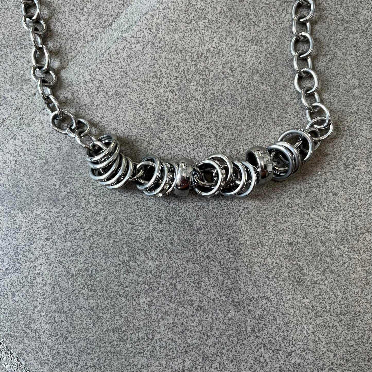 Dolce &amp; Gabbana DJ0776 Crystal Ring Link Necklace features a long stainless steel chain with freely moving rings, including basic loops, D&amp;G-engraved rings and crystal-set rings. The necklace has a large clasp, while the end is finished with a ball featuring D&amp;G logos all around it.
