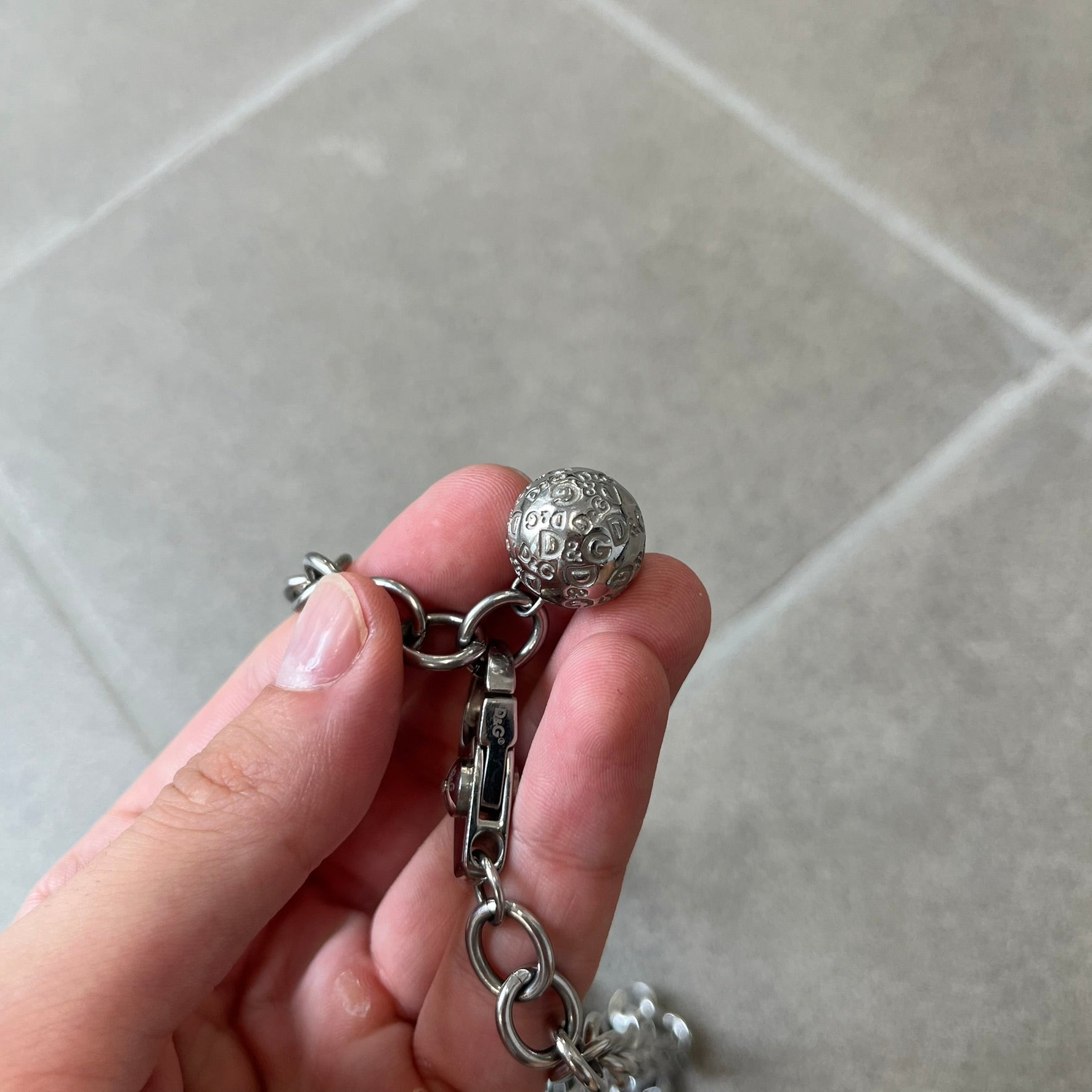 Dolce &amp; Gabbana DJ0776 Crystal Ring Link Necklace features a long stainless steel chain with freely moving rings, including basic loops, D&amp;G-engraved rings and crystal-set rings. The necklace has a large clasp, while the end is finished with a ball featuring D&amp;G logos all around it.